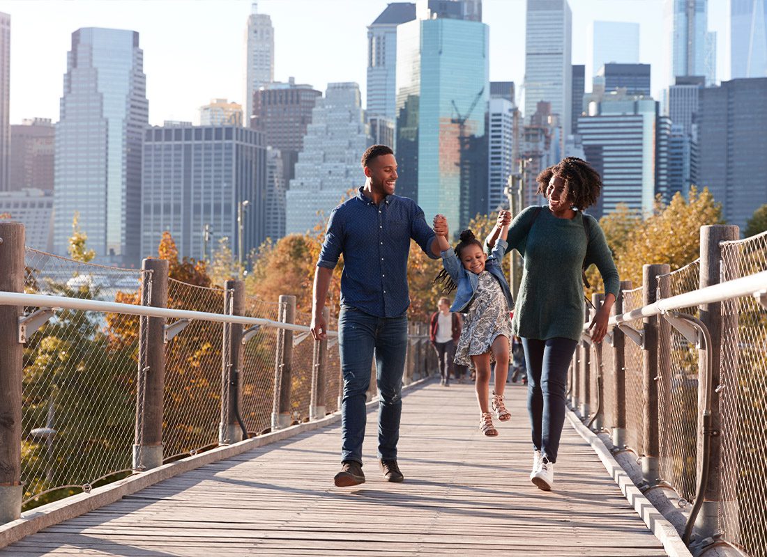 Personal Insurance - Young Family With Daughter Taking a Walk on Footbridge
