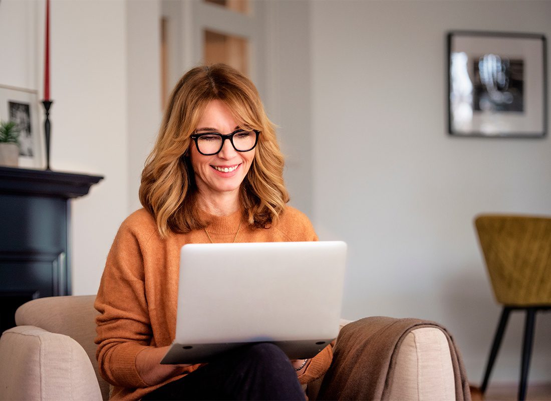 Blog - Middle Aged Woman Looking at Her Laptop While Smiling