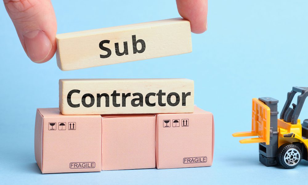 Is Your Sub-Contractor Putting You at Risk? Protect Your Business! - Toy Forklift With Tiny Boxes And A Hand Placeing Blocks That Say Sub Contractor On Top