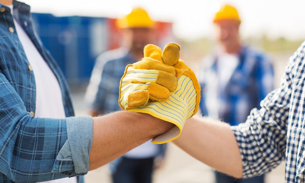 Action Over Exclusion Explanation - Why Collaboration Matters - Two construction workers shaking hands