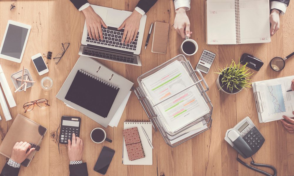 Simplifying Insurance Quotes/ A Comprehensive Guide for Businesses - Business people at a conference table full of laptops and office supplies working